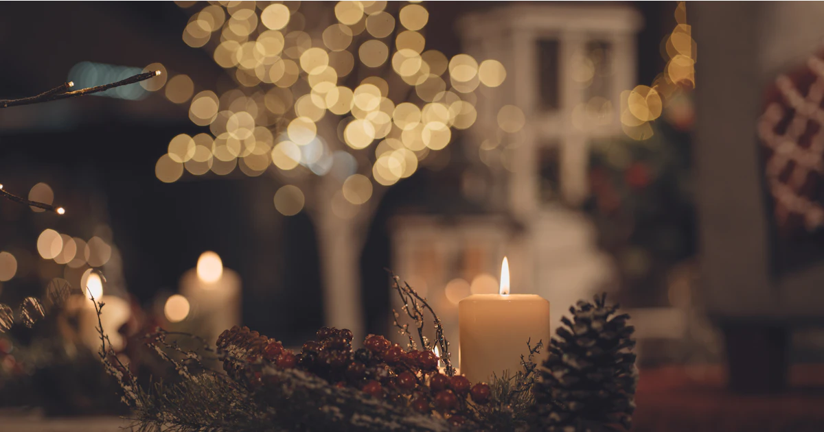 Tända ljus med kottar och granris på ett bord i juletid