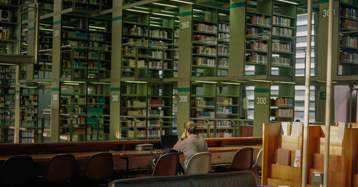 Student som pluggar vid ett bord i ett stort bibliotek
